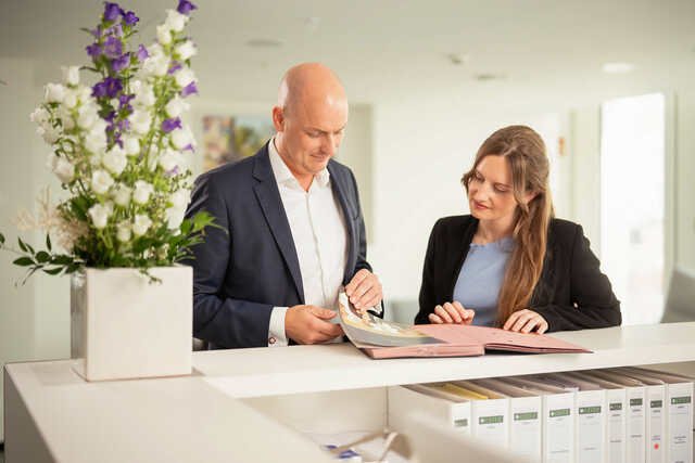 Eine Anwältin und ein Anwalt stehen an einer Theke mit Akten vor ihnen