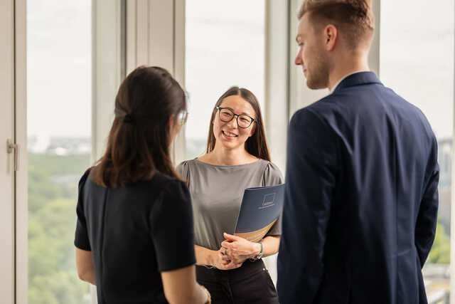 Eine Anwältin im Gespräch mit zwei Kolleg:innen