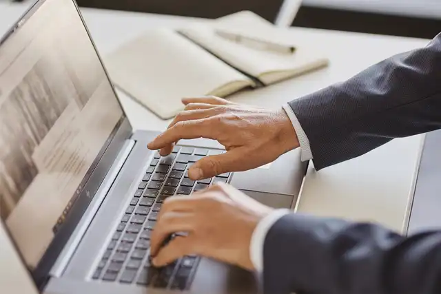 Hände die etwas in eine Laptop Tastatur eingeben 