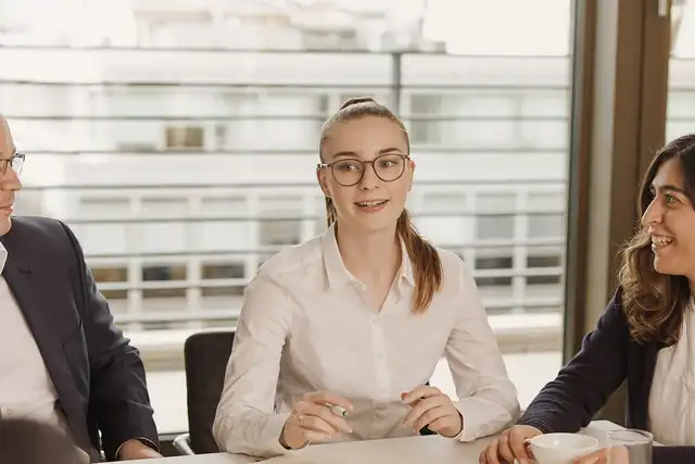 Eine Frau sitzt an einem Tisch und erklärt etwas.