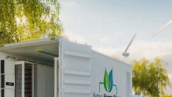 Ein Container zur Energiespeicherung vor Windrädern und Solarzellen