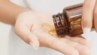 Kapseln aus einem Behältnis werden in eine Handfläche geschüttet