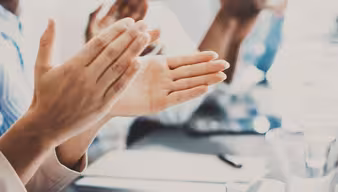 Hände die applaudieren an einem Schreibtisch