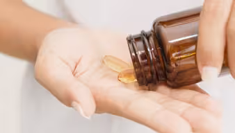 Kapseln aus einem Behältnis werden in eine Handfläche geschüttet